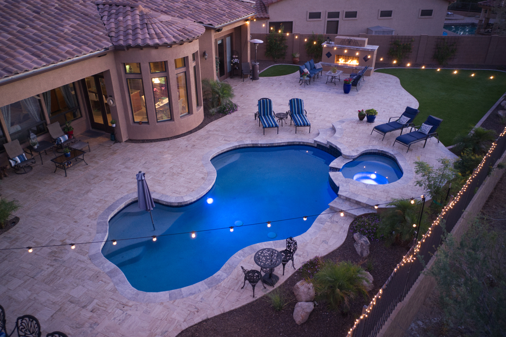 An aerial view of a luxurious outdoor area featuring a swimming pool, spa and outdoor gas fireplace.