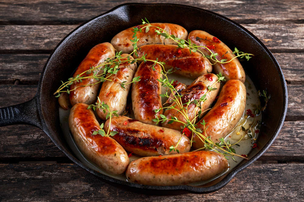Perfectly cooked BBQ sausages in a skillet garnished with herbs.