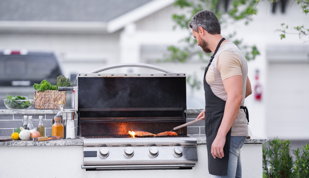 A man cooking seafood on a built-in barbecue in his backyard. 