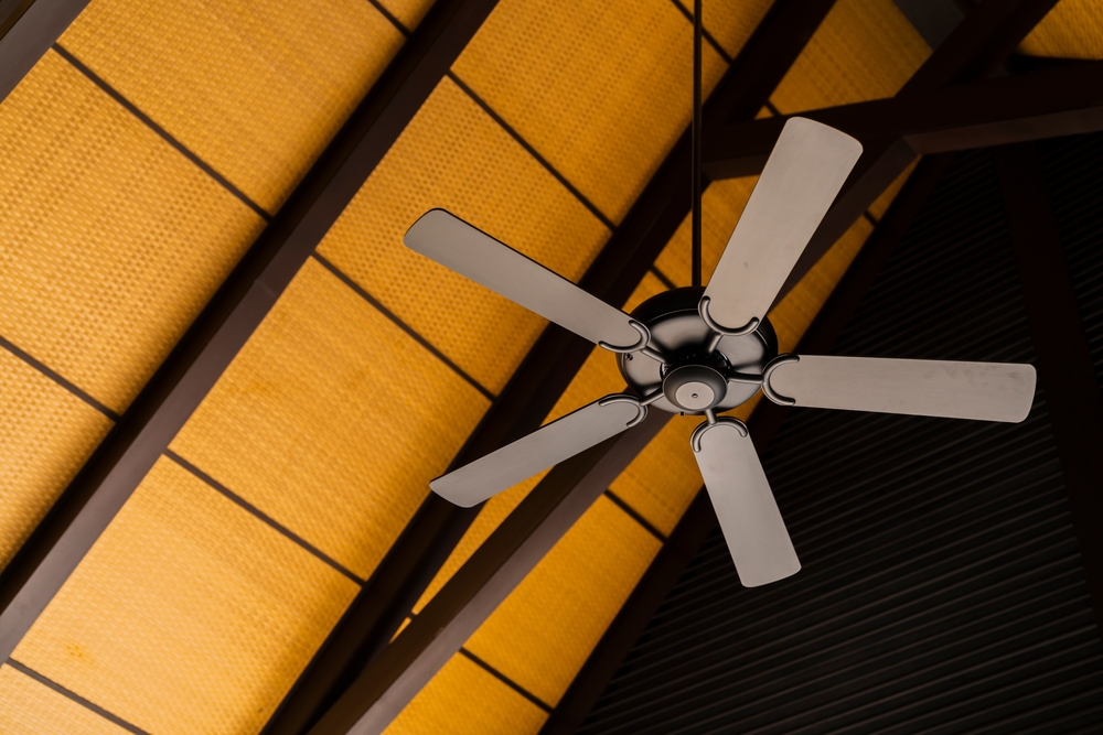 A brown ceiling fan contrasted with wood panel ceiling.