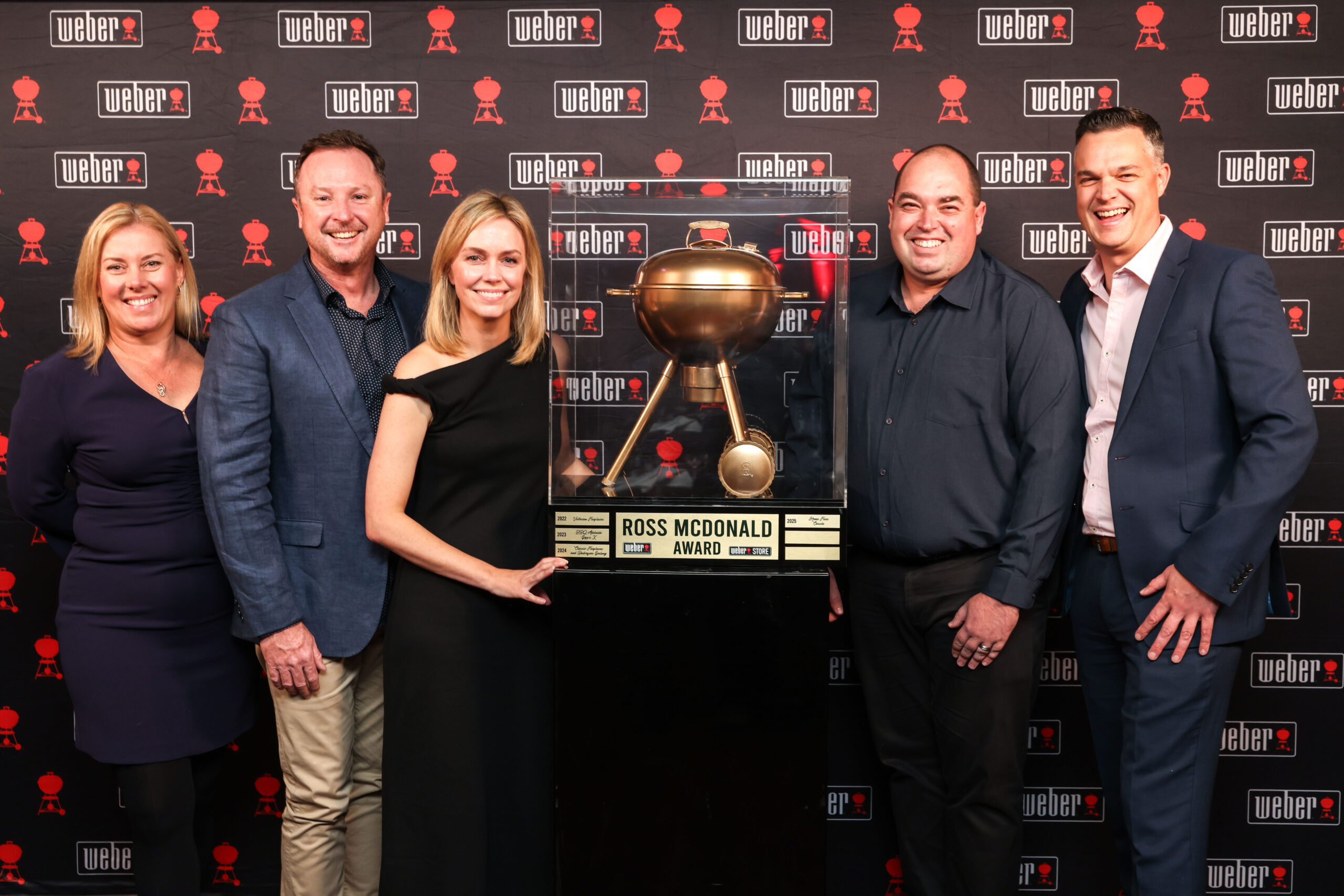 The Home Fires Team pose with their Ross McDonald Award for Most Outstanding Weber Store 2025 for Australia and New Zealand. Everyone is smiling and very proud.