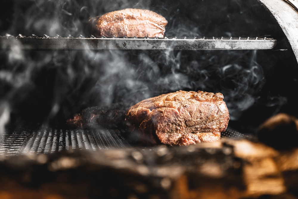 Meat being smoked on a BBQ using the low and slow method for autumn BBQ recipes. 