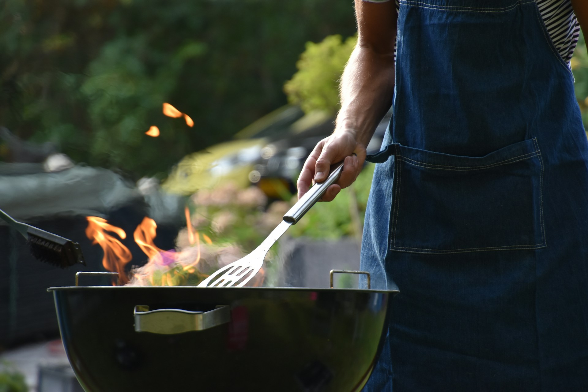 A man cooking on a BBQ in his backyard.