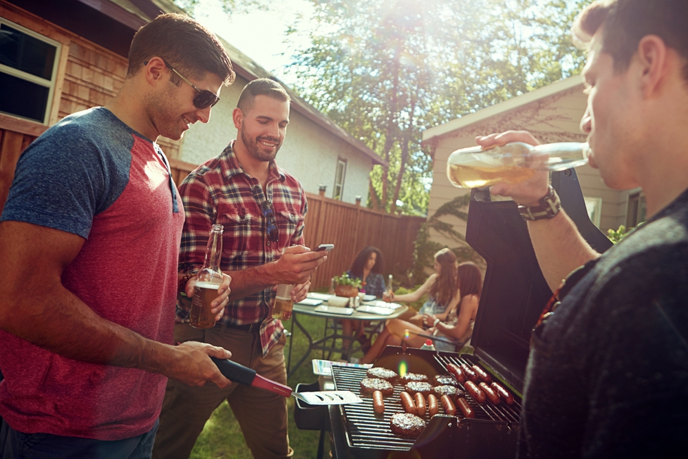 Three blokes standing around a BBQ discussing summer BBQ tips in Australia.