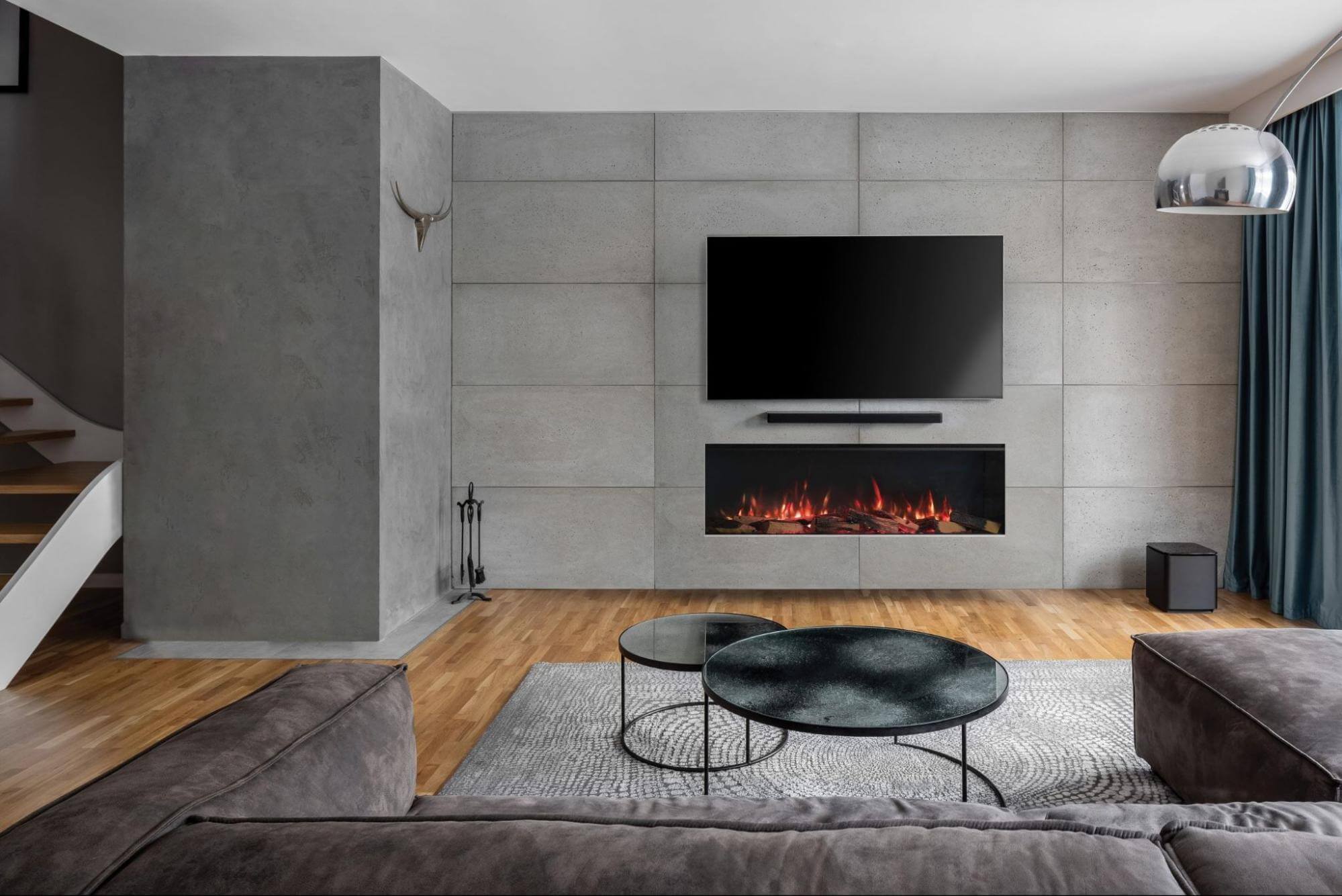 A wall-mounted inbuilt electric fireplace positioned perfectly beneath a large flat-screen TV on a textured concrete-look feature wall