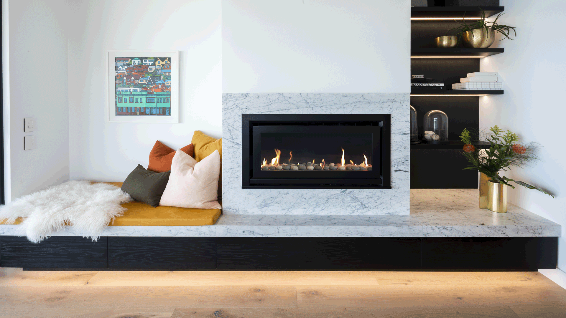 A modern indoor gas fireplace styled seamlessly into a custom marble surround with a cosy seating nook.