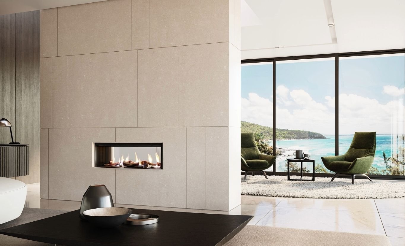 A modern double-sided gas fireplace built into a minimalist stone feature wall separating two light-filled living zones with coastal views.