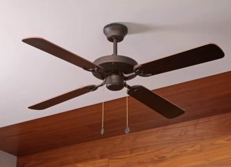 A dark ceiling fan on a wooden and white ceiling.