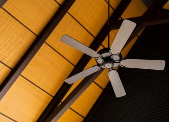 A brown ceiling fan contrasted with wood panel ceiling.