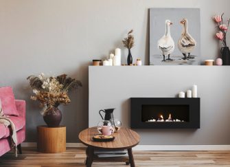 A sleek, wall-mounted black gas fireplace provides a warm glow in a modern, stylishly decorated living room.